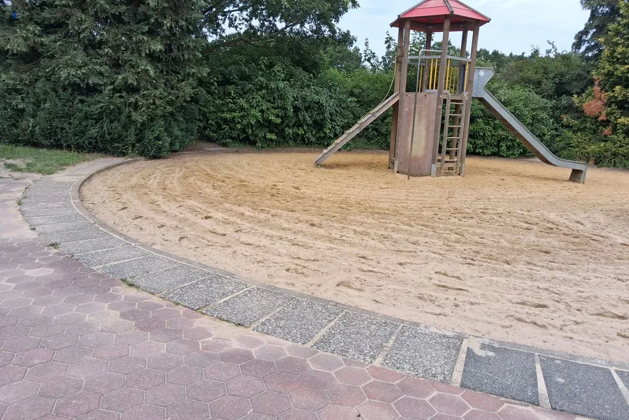 Gepflegte Sandfläche und Spielturm auf einem Spielplatz